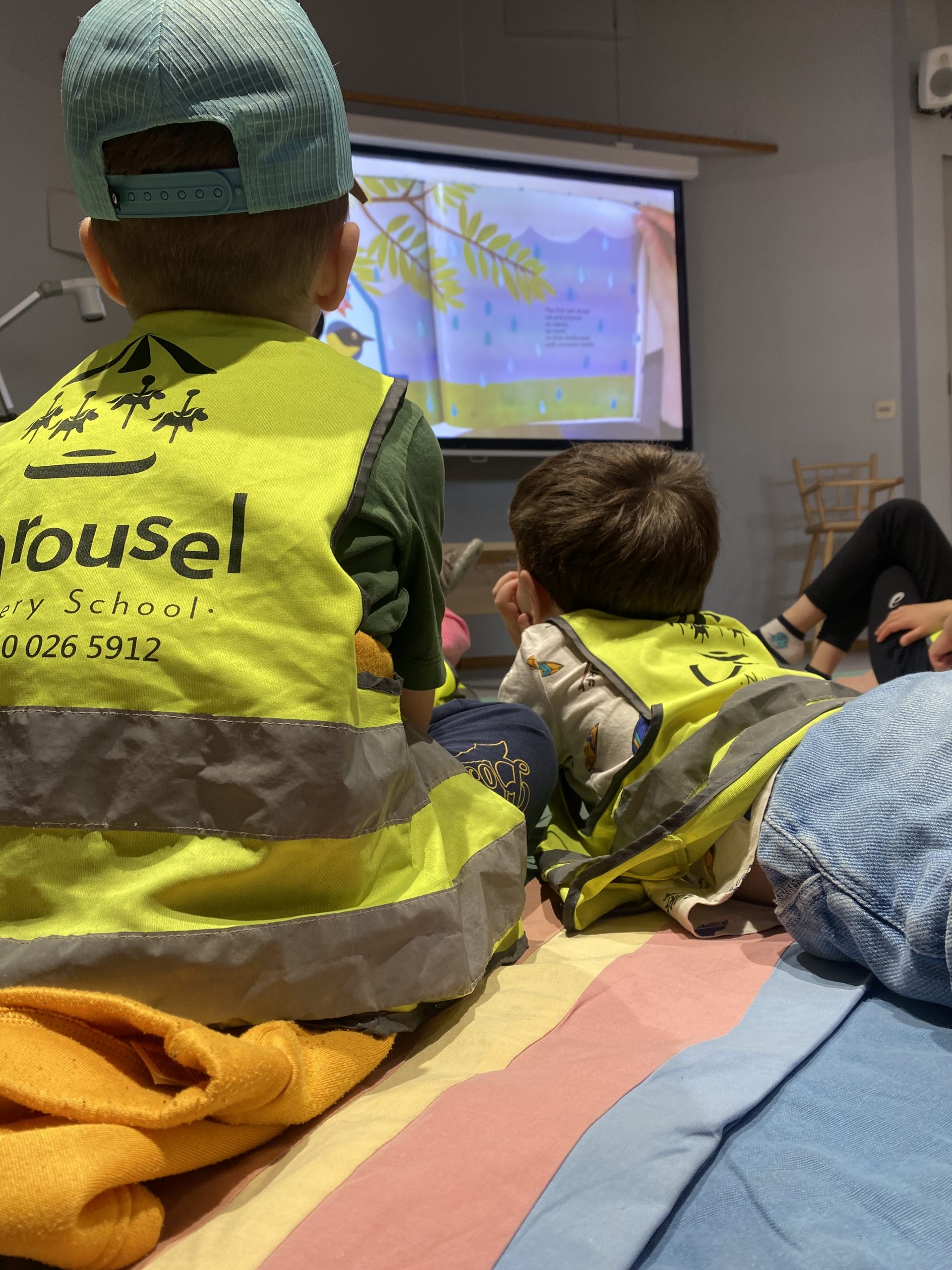Children seen from behind enjoying an illustrated story at Kallio Library