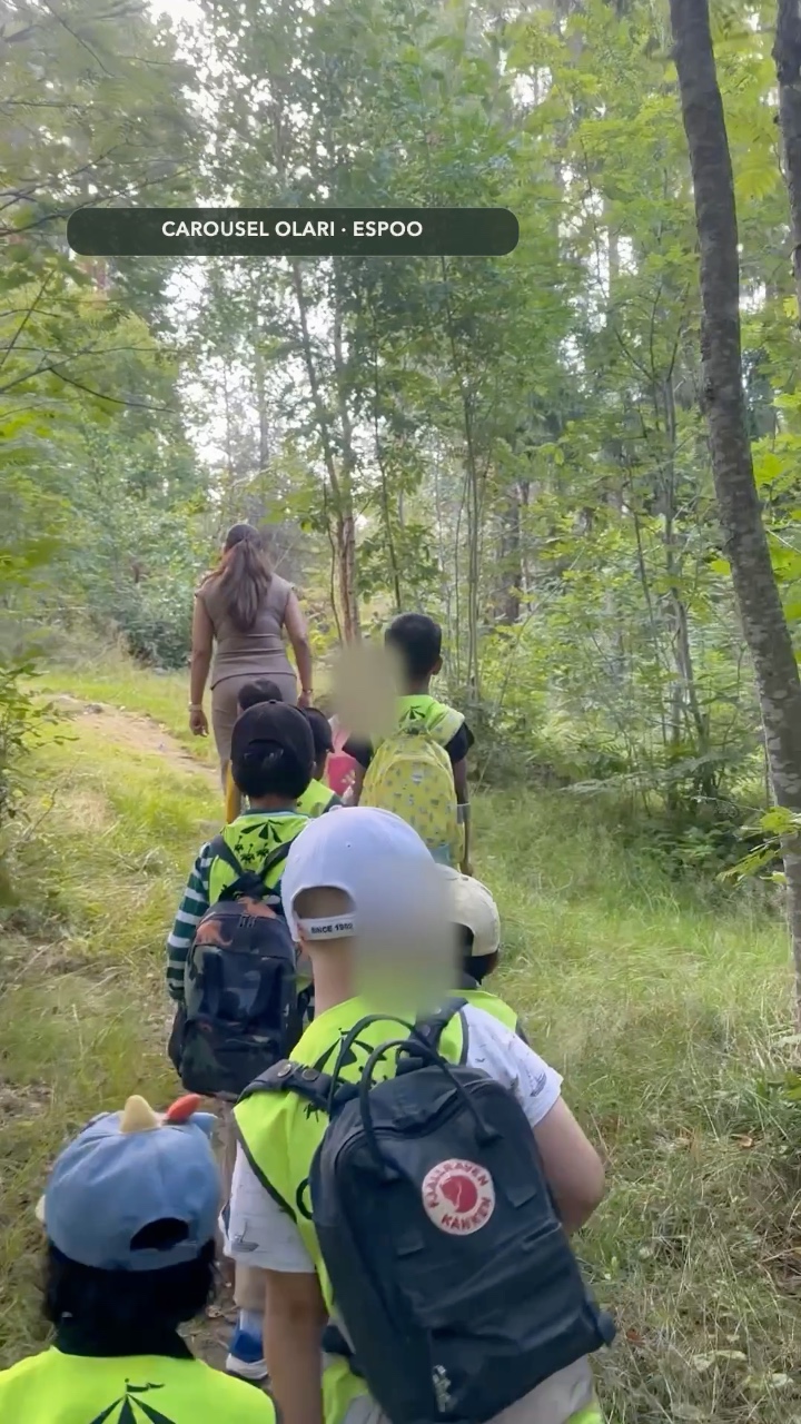 Olari children and an educator walking together along a woodland path, with children's faces blurred
