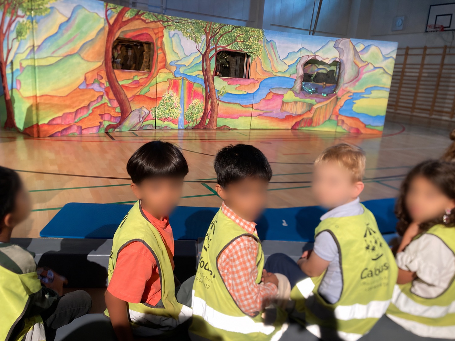 Olari children seated in front of a colourful mini-opera stage